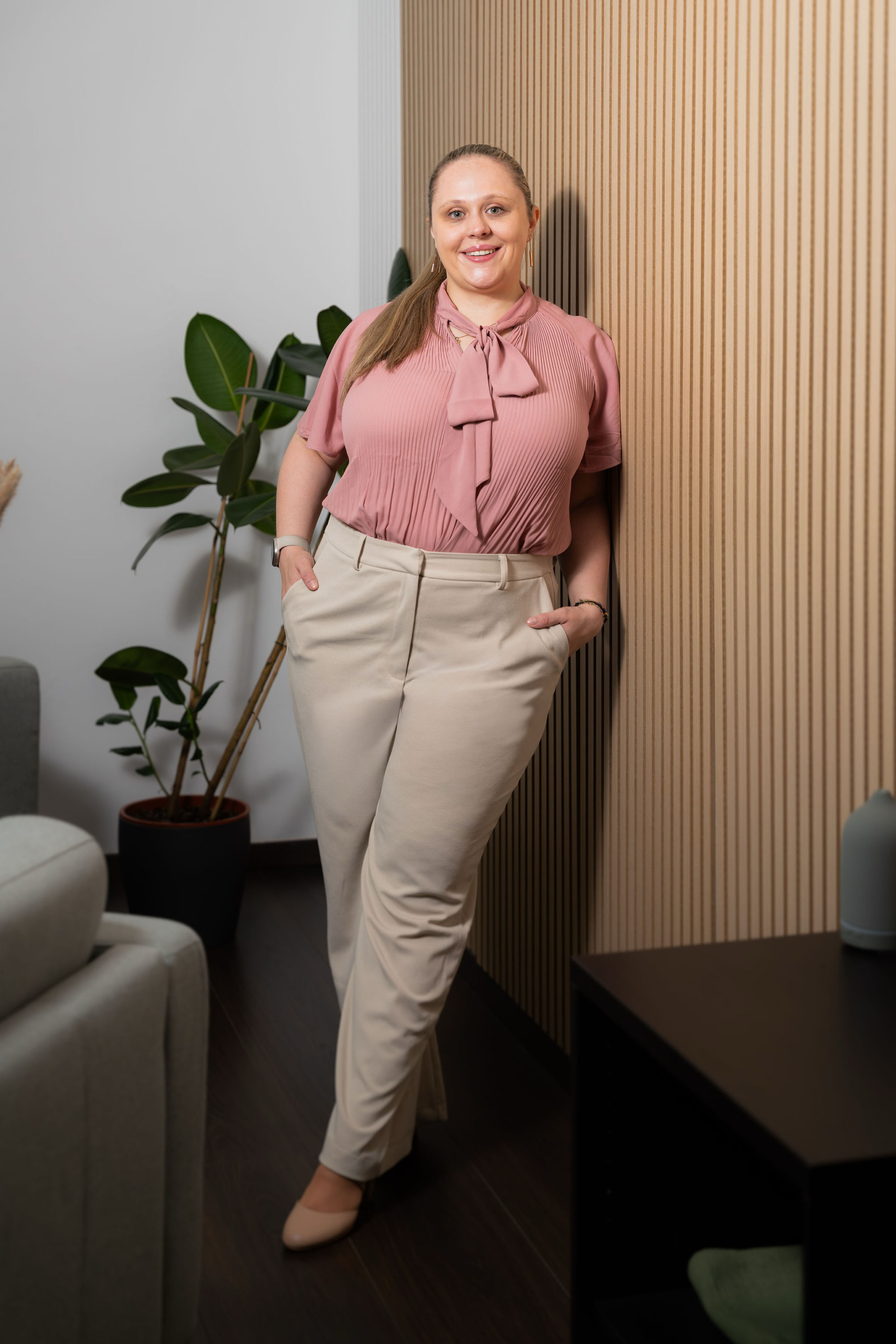 Romana, Hochzeitsplanerin in Wien, lehnt an einer Wand mit Holzlamellen