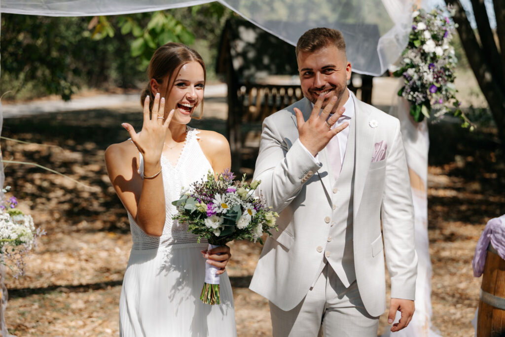 Frisch verheiratetes Paar zeigt seine Eheringe im Outdoor‑Setting
